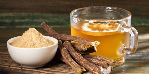 a bowl of licorice powder, dried licorice root, and a mug of licorice tea