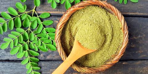 Benefits of Moringa a bowl of moringa powder and fresh leaves