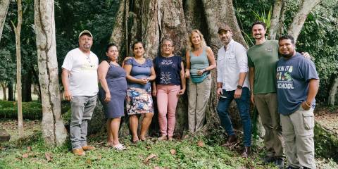 Caroline standing at the edge of a rainforest with some of her workers and farmers