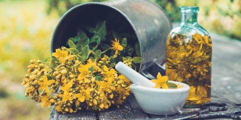 St. John's Wort for Seasonal Depression St. John's Wort in a bucket next to a bottle of tincture and a mortar and pestle..