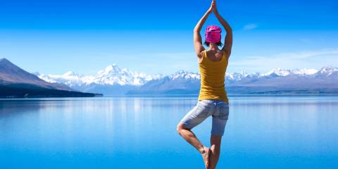 Supplements to Regulate Hormones A young woman doing a yoga pose for balance on a rock overlooking a lake.