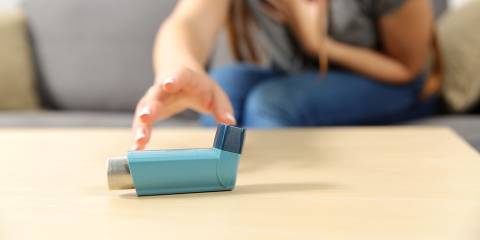 a woman having an asthma attack reaching for her rescue inhaler
