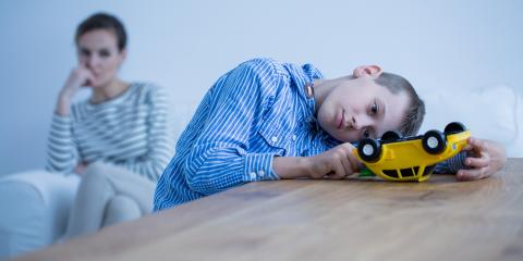 An autistic boy playing with a truck while his mother watches