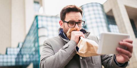 a man breathing into a paper bag while he reads the news