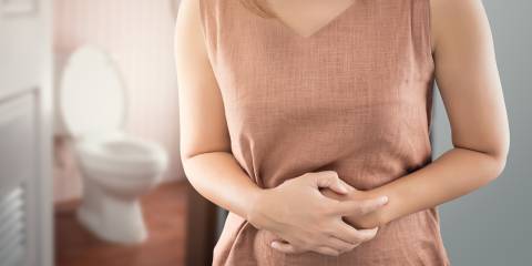 A woman outside the bathroom with bowel cramps from bloating