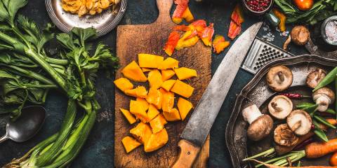 a kitchen knife on a cutting board of sliced and diced fruits and vegetables