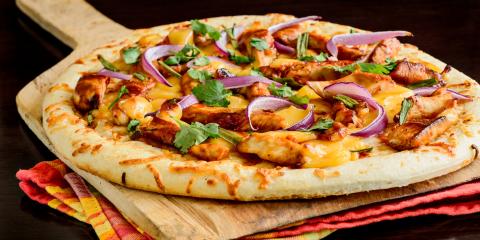 Grilled pizza with meat and purple onions on top of colorful cloths.