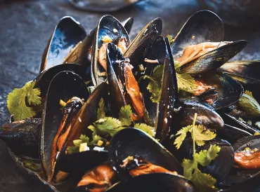 Grilled mussels served on a dark platter