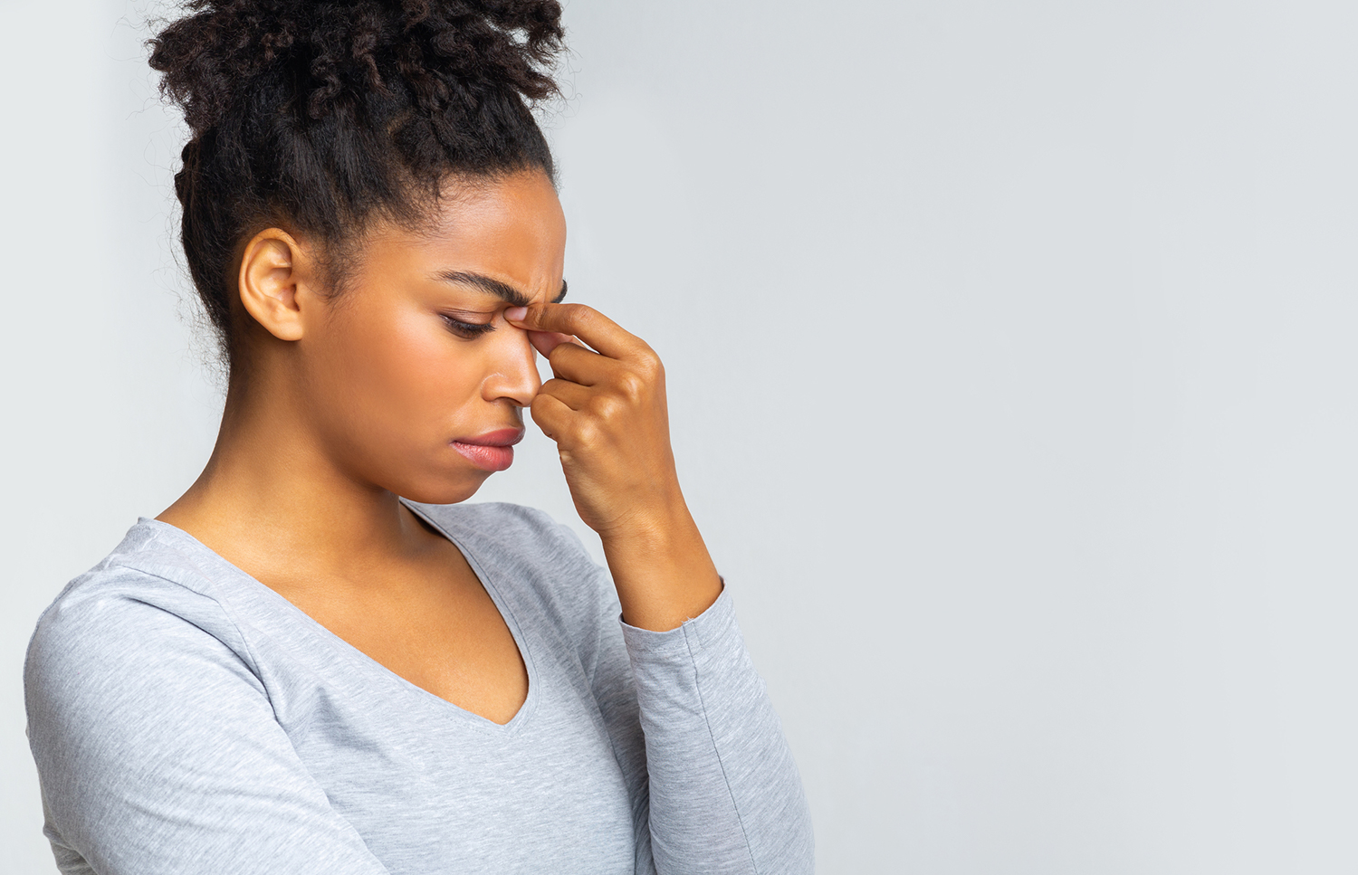 Herbs for Sinus Relief a young woman holding the bridge of her nose due to sinus pain