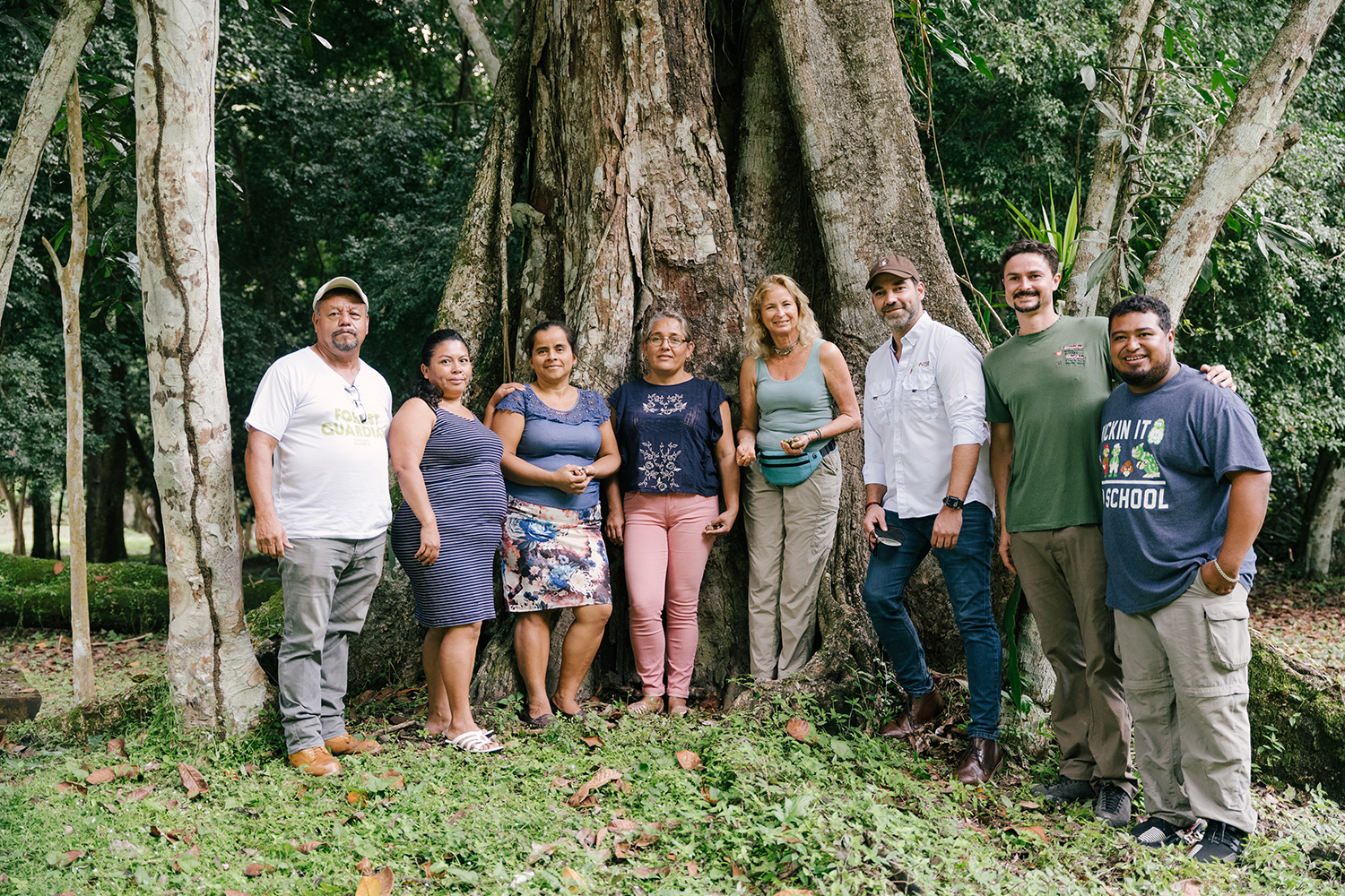 Caroline standing at the edge of a rainforest with some of her workers and farmers
