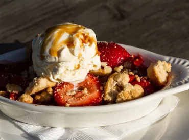 a dish of strawberry-rhubarb crisp topped with ice cream